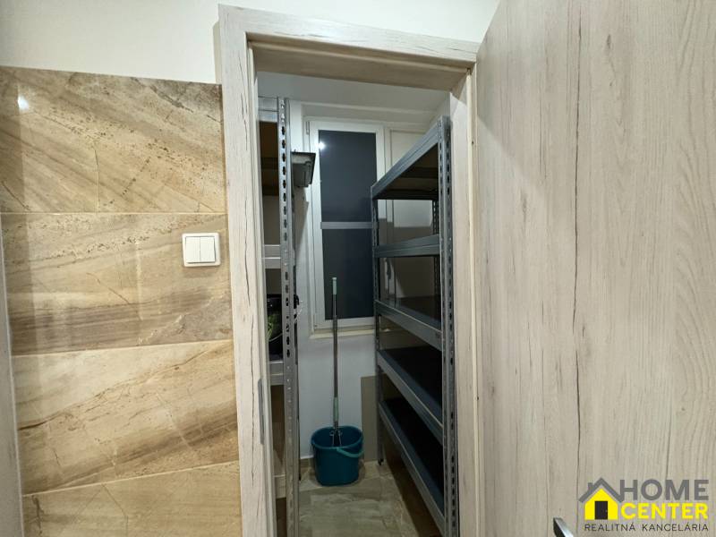 Malý sklad ve 3-pokojovém bytě s regály a kbelíkem.