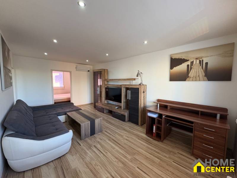 Obývací pokoj v 3-pokojovém bytě s podlahou s dřevěným dekorem a pohodlnou sedací soupravou.