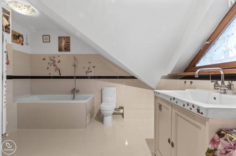 Koupelna v rodinném domě s vanou, toaletou a dekorativními nálepkami na stěnách.