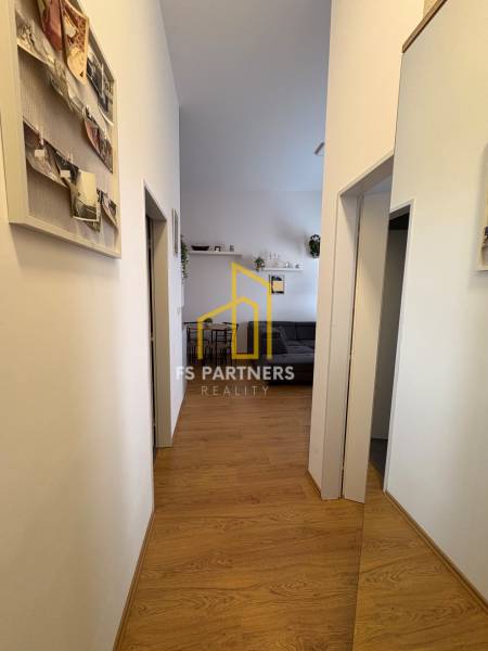 Chodba v 2-pokojovém bytě s podlahou s dřevěným dekorem a dekoracemi na stěnách.