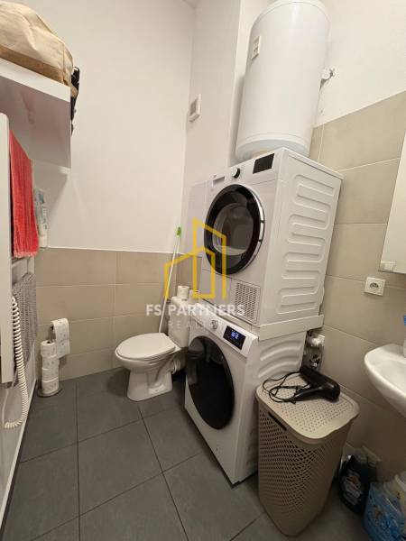 Koupelna v 2-pokojovém bytě s pračkou, sušičkou, toaletou a umyvadlem.