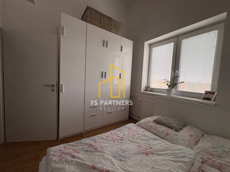 Ložnice v 2pokojovém bytě s podlahou s dřevěným dekorem a velkou skříní.