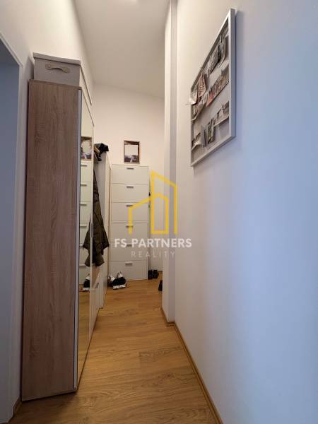 Úzká chodba v 2-pokojovém bytě s podlahou s dřevěným dekorem a šatníkem.