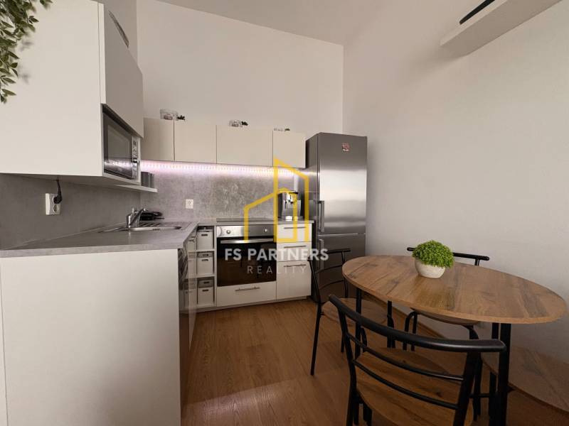 Kuchyně v 2pokojovém bytě s podlahou s dřevěným dekorem a jídelním stolem.