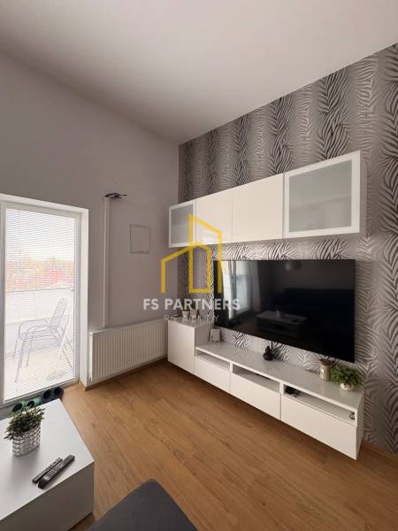 Obývací pokoj s TV stěnou, vzorovanou tapetou a podlahou s dřevěným dekorem v 2pokojovém bytě.