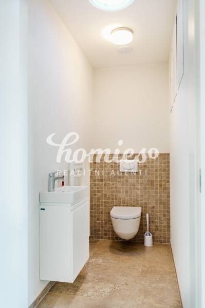 Toaleta s umyvadlem, stěnami ve světlých barvách a dlažbou v rodinném domě.