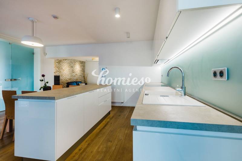 Kuchyně s ostrůvkem, cihlovou stěnou a podlahou s dřevěným dekorem v rodinném domě.