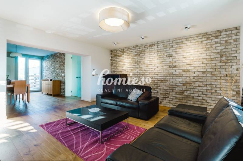 Obývací pokoj v rodinném domě s cihlovou stěnou a podlahou s dřevěným dekorem.