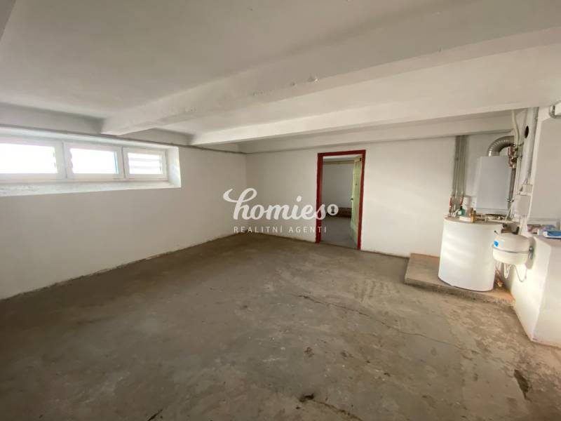 Prázdná místnost v rodinném domě s okny a kotlem.