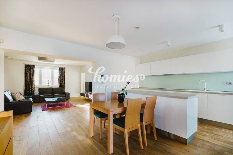 Kuchyň a obývací pokoj v rodinném domě s podlahou s dřevěným dekorem a světlým nábytkem.