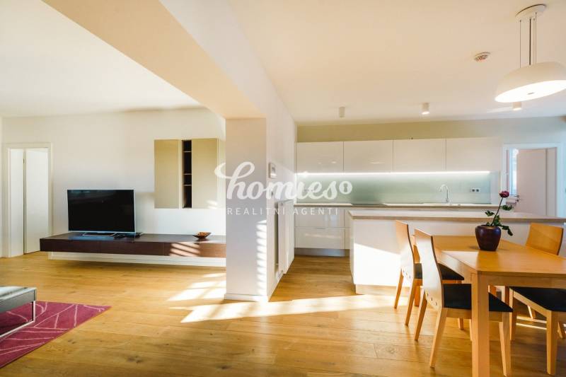 Rodinný dům s otevřenou kuchyní, dřevěným dekorem podlahy a jídelním stolem.