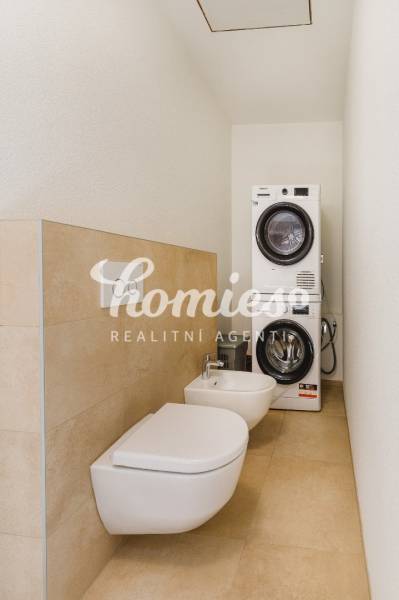 Koupelna v rodinném domě s pračkou, sušičkou, bidetem a toaletou.