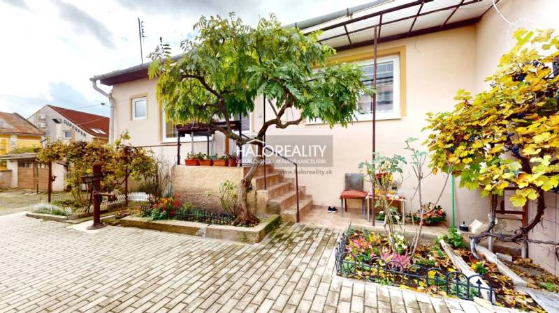 Rodinný dům v Lučenci s upraveným dvorem, květinovou zahradou a cihlovou dlažbou.
