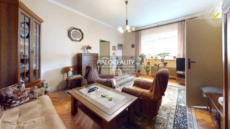 Obývací pokoj s rustikálním nábytkem, květinami a podlahou s dřevěným dekorem v rodinném domě.