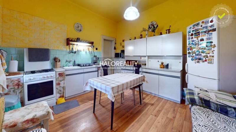 Jasná kuchyně v rodinném domě s bílými skříňkami a podlahou s dřevěným dekorem.