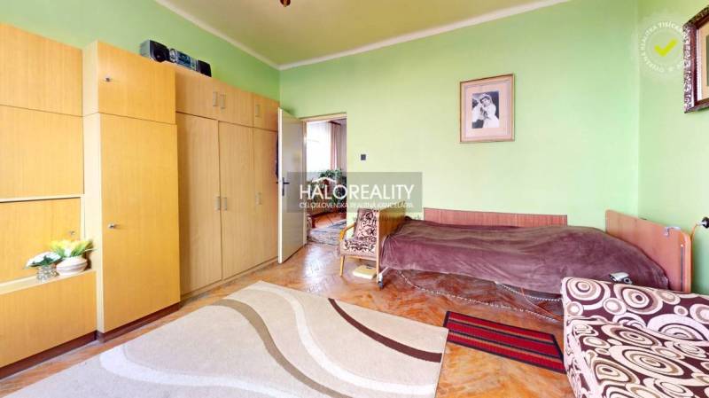 Pokoj v rodinném domě s podlahou s dřevěným dekorem, zelené stěny, nábytek, obrázky.