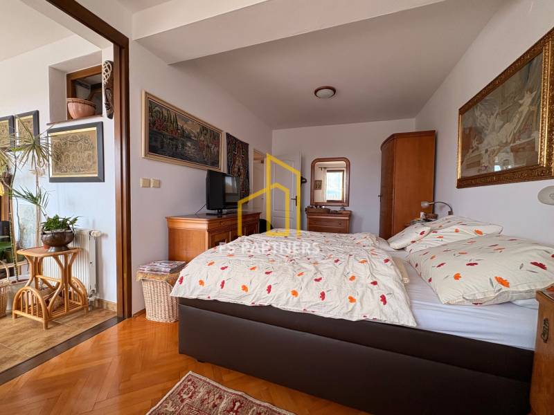 Pokoj v 5 a více pokojovém bytě s postelí, uměním na stěnách a podlahou s dřevěným dekorem.