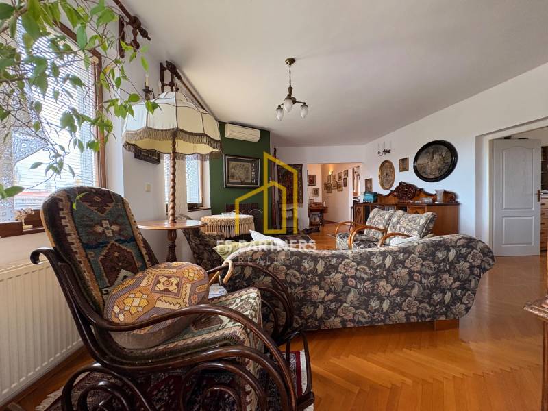 Obývací pokoj v bytě s 5 a více pokoji s podlahou s dřevěným dekorem a vintage nábytkem.