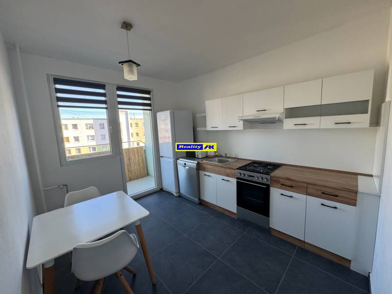 Kuchyně v 3-pokojovém bytě s bílým nábytkem a jídelním stolem.