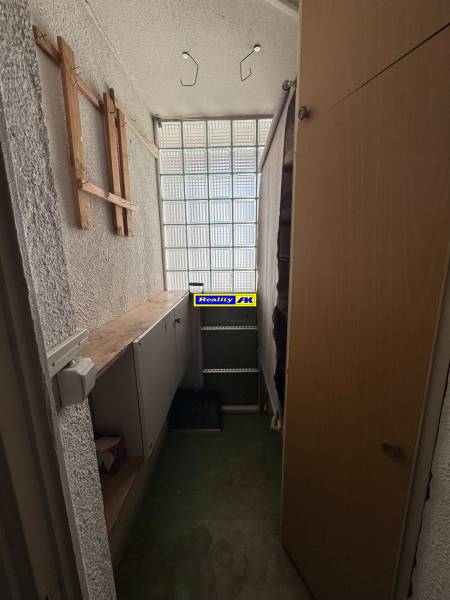 Úložný prostor v 3-pokojovém bytě s regály a prosklenou stěnou.