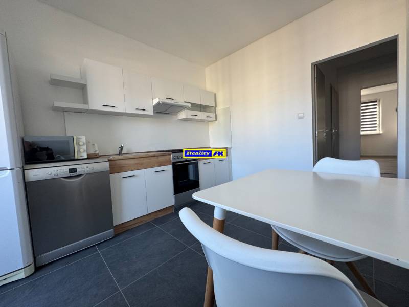 Kuchyně 3pokojového bytu s bílým nábytkem a spotřebiči, podlaha z keramických dlaždic.