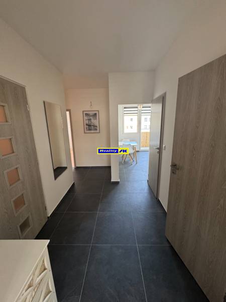 Vstupní chodba v 3pokojovém bytě s tmavou podlahou a světlými stěnami.