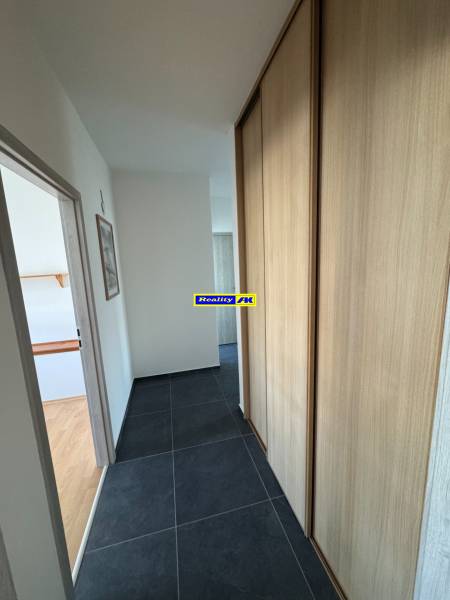 Chodba ve 3-pokojovém bytě s tmavou dlažbou a vestavěnou skříní.