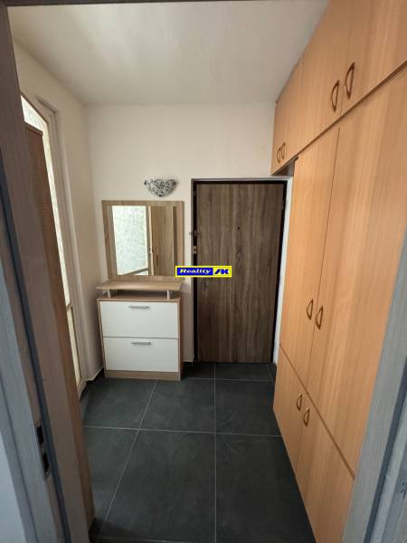 Chodba s tmavou dlažbou a vestavěnou skříní v 3pokojovém bytě.