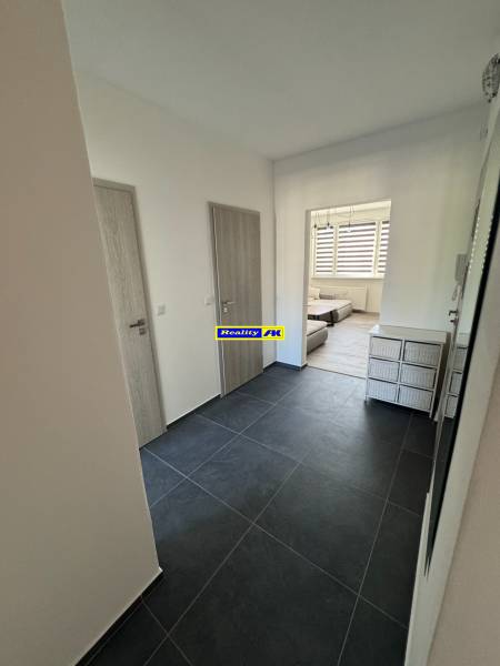 Vstupní chodba v 3-pokojovém bytě s tmavou dlažbou a světlými dveřmi.