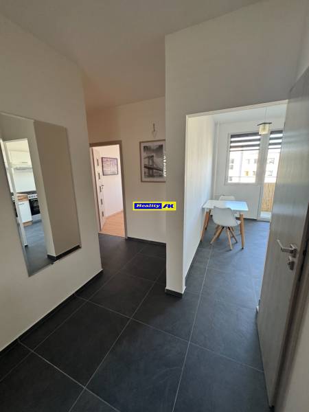 Chodba s tmavou dlažbou a jídelnou v 3-pokojovém bytě.