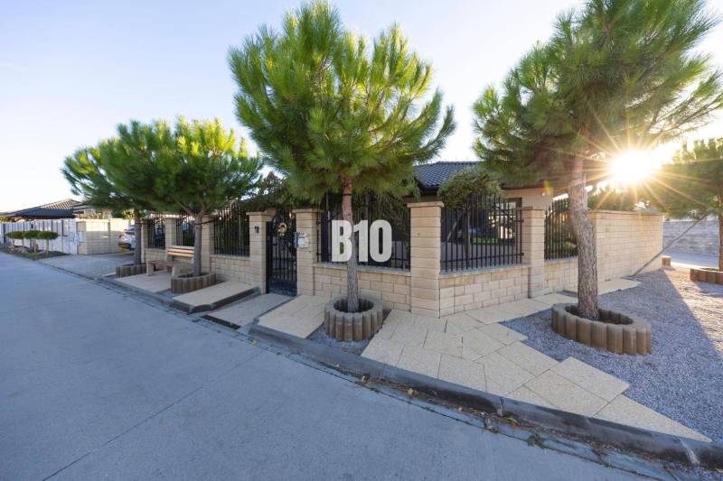 Rodinný dům v Mostě u Bratislavy s kamenným plotem a výsadbou stromů.