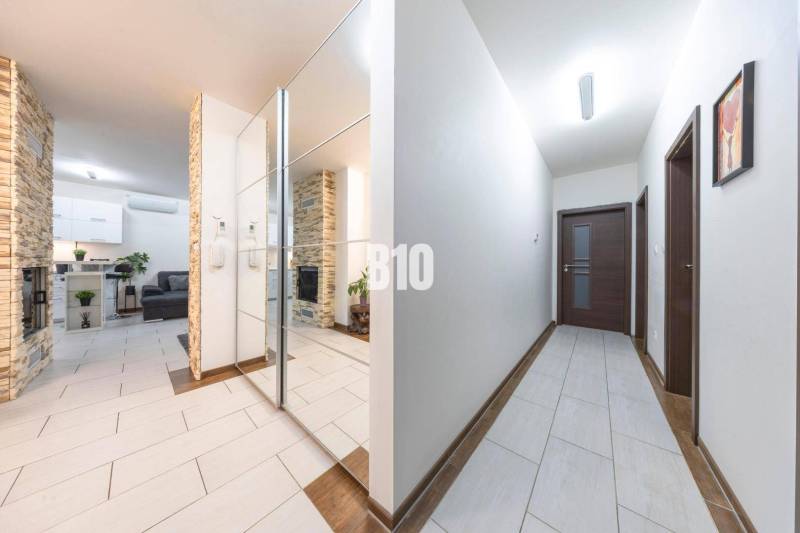 Chodba rodinného domu s dlažbou a zrcadlovou stěnou.