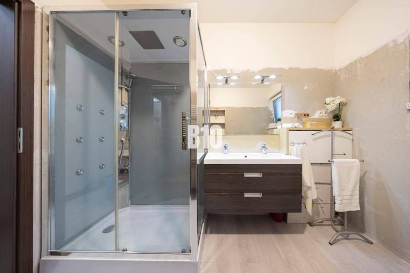 Koupelna v rodinném domě s podlahou s dřevěným dekorem, sprchovým koutem a zrcadlem.