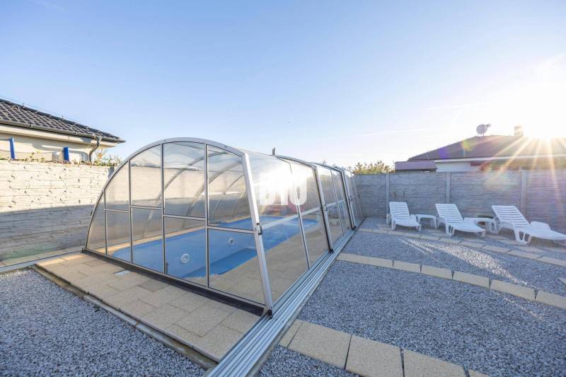 Zahrada rodinného domu v Mostě u Bratislavy s bazénem a lehátky.