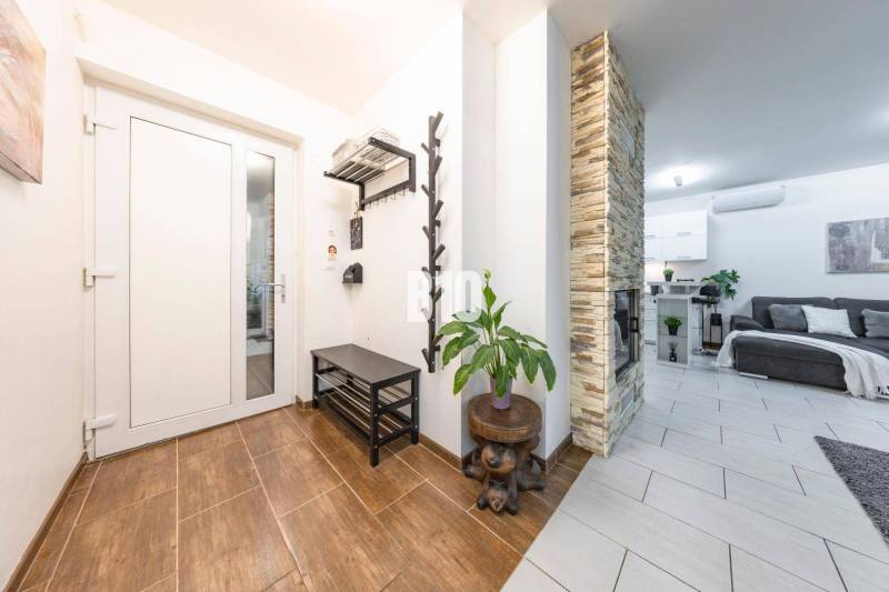 Interiér rodinného domu s podlahou s dřevěným dekorem, kamenným krbem a pohodlným obývacím pokojem.