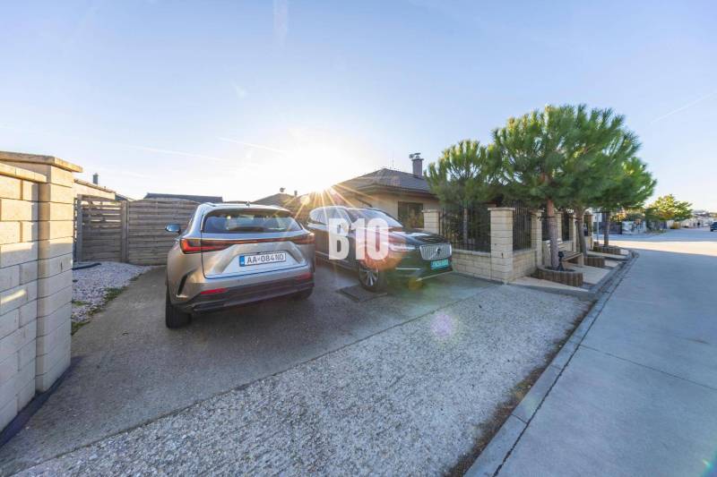 Dvorek rodinného domu v Mostě u Bratislavy s parkovacími místy a zaparkovanými auty.