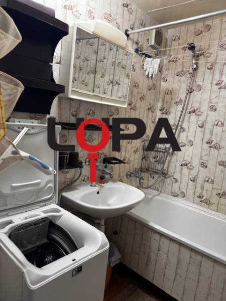 Koupelna v 3-pokojovém bytě s vanou, umyvadlem a pračkou, tapetová dekorace.