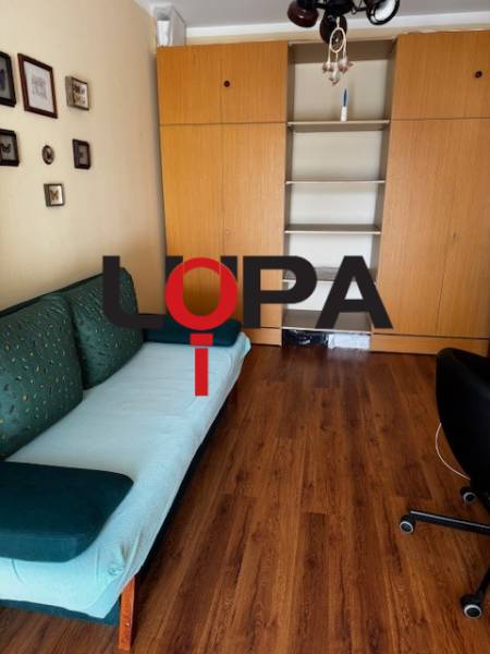 Pokoj v 3-pokojovém bytě s podlahou s dřevěným dekorem a vestavěnými skříněmi.