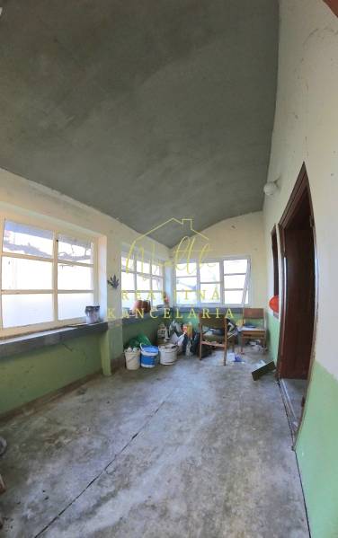 Interiér rodinného domu se starými okny a podlahou z betonu.