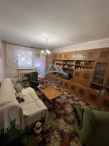 Obývací pokoj ve 3-pokojovém bytě s dřevěnou obývací stěnou a pohodlným sezením.