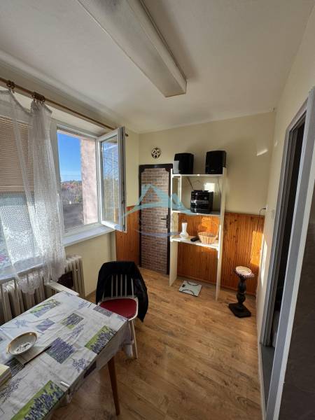 Jídelna v 3-pokojovém bytě s podlahou s dřevěným dekorem a otevřeným oknem.