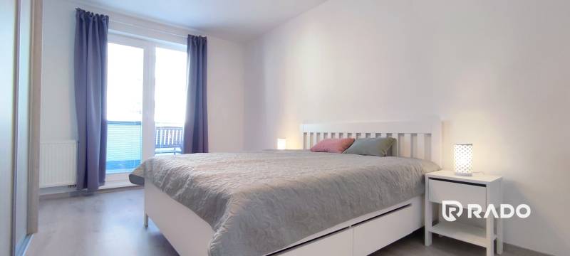 Ložnice v 2-pokojovém bytě se světlým nábytkem a podlahou s dřevěným dekorem.