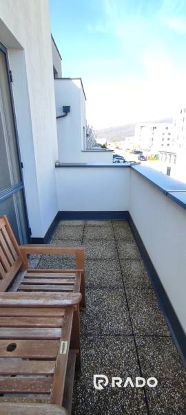 Balkon s lavicí v 2-pokojovém bytě na ulici Predmerského, Trenčín, s výhledem na město.