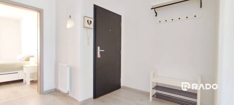 Vstupní chodba se světlými stěnami a podlahou s dřevěným dekorem vede do ložnice.