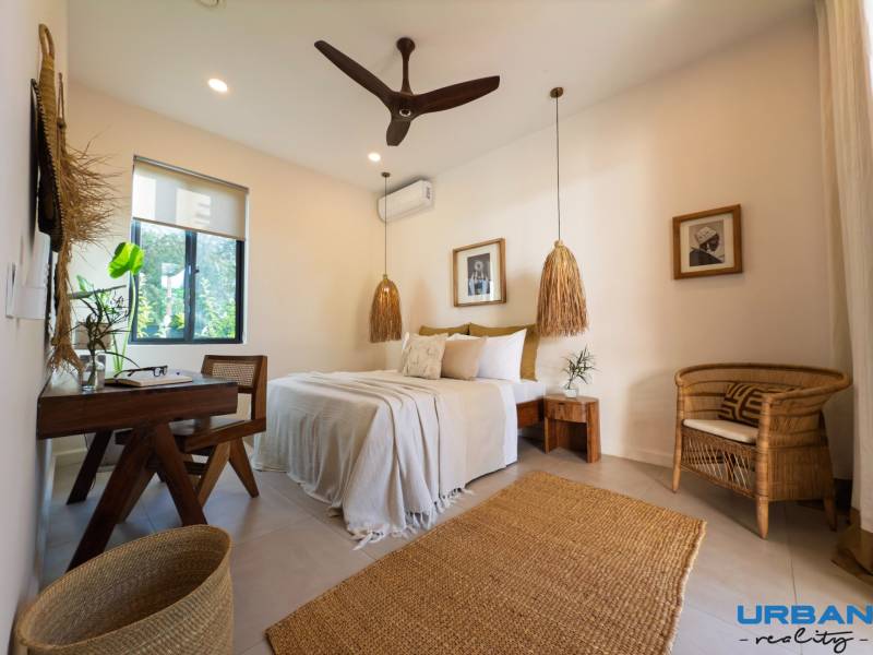 Světlá ložnice se závěsnými lampami a proutěným nábytkem v rodinném domě.