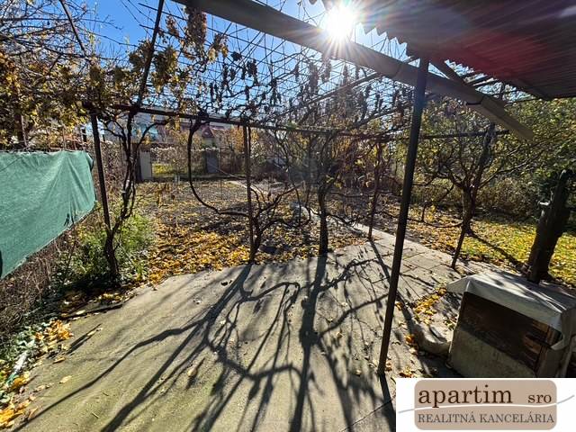 Podzimní zahrada v Bratislavě - Ružinov na Střední ulici s pergolou a opadanými listy.