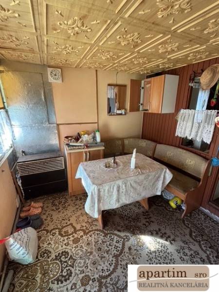 Interiér chaty se starožitným vzorovaným stolem a dřevěnými detaily v Zahradách.