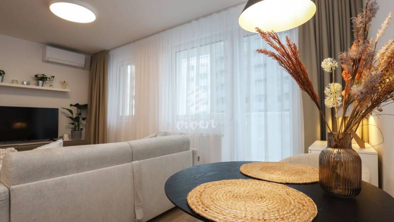 Obývací pokoj v jednopokojovém bytě s pohodlným sezením a dekorativními prvky.