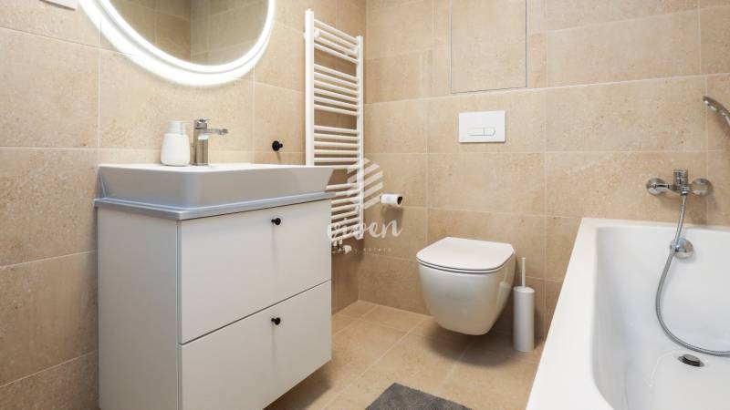 Koupelna v 1-pokojovém bytě s umyvadlovou skříňkou, WC a vanou.