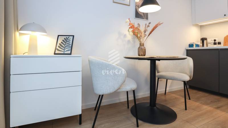 1-pokojový byt s dekorativními židlemi, stolem a lampou na podlaze s dřevěným dekorem.